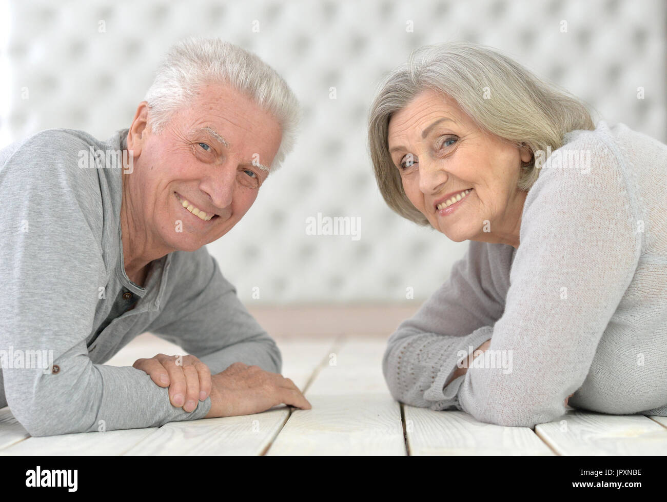 Portrait of happy senior couple lying on floor Banque D'Images