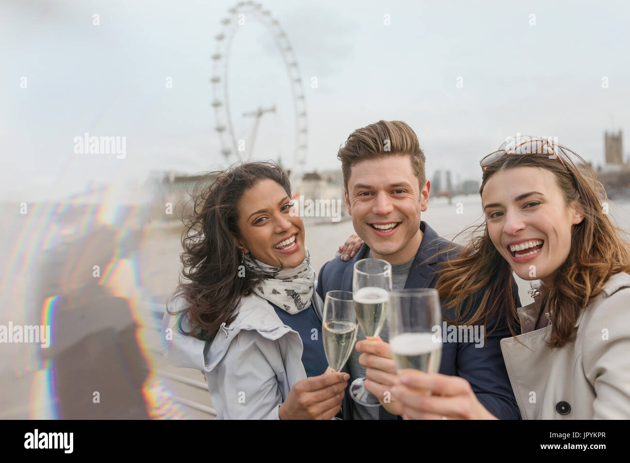Portrait enthousiaste, smiling friends toasting champagne, près de roue du millénaire, London, UK Banque D'Images
