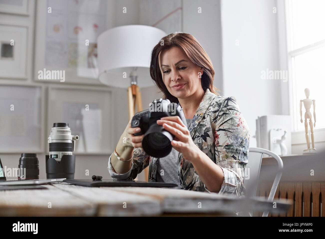 Femme photographe using digital camera in office Banque D'Images