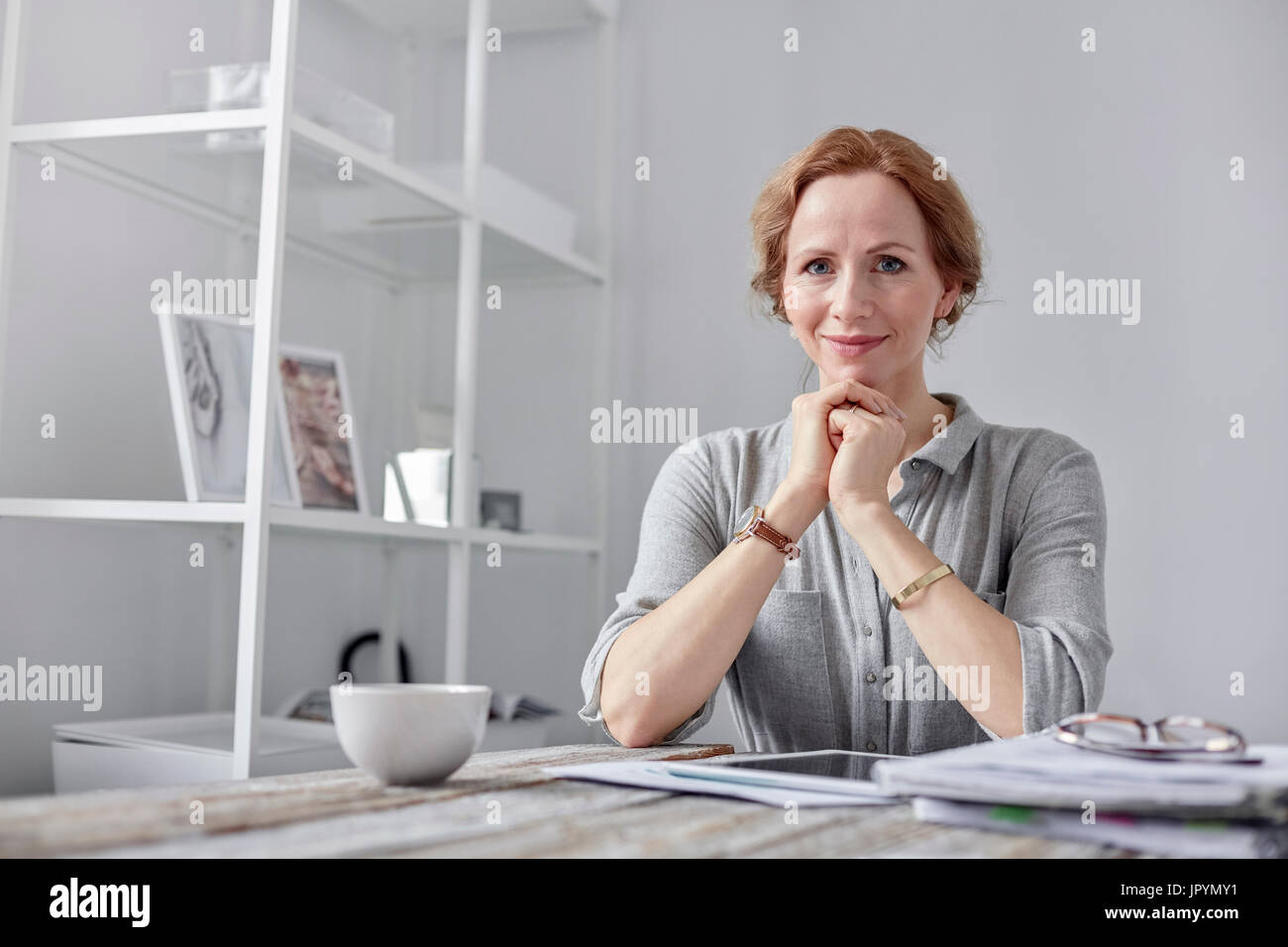 Portrait souriant, confiant businesswoman using digital tablet in office et boire le thé Banque D'Images