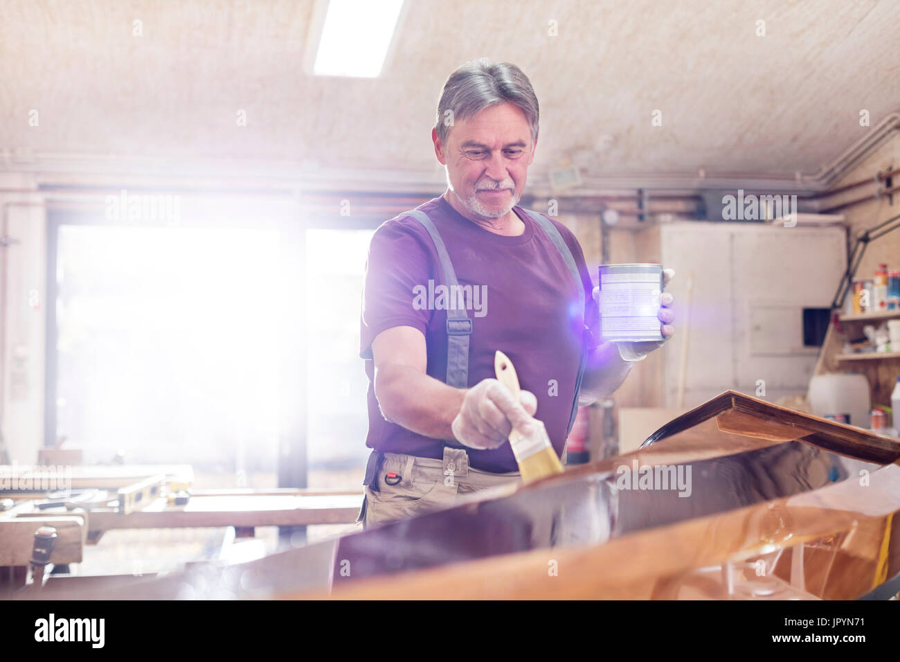 Male carpenter la teinture du bois kayak en atelier Banque D'Images