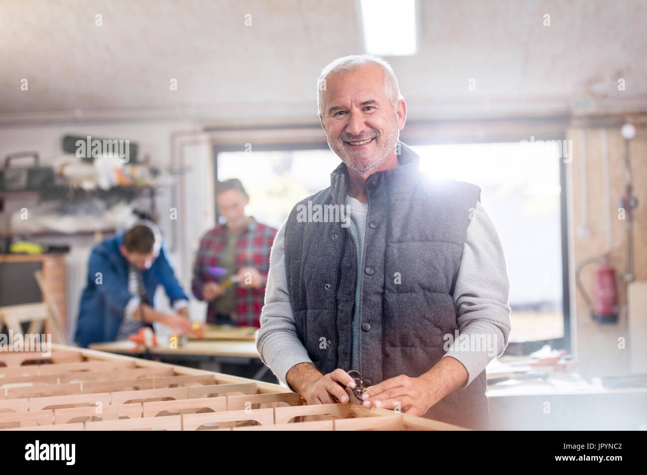 Portrait of smiling male menuisier travaillant sur bateau en bois dans l'atelier Banque D'Images