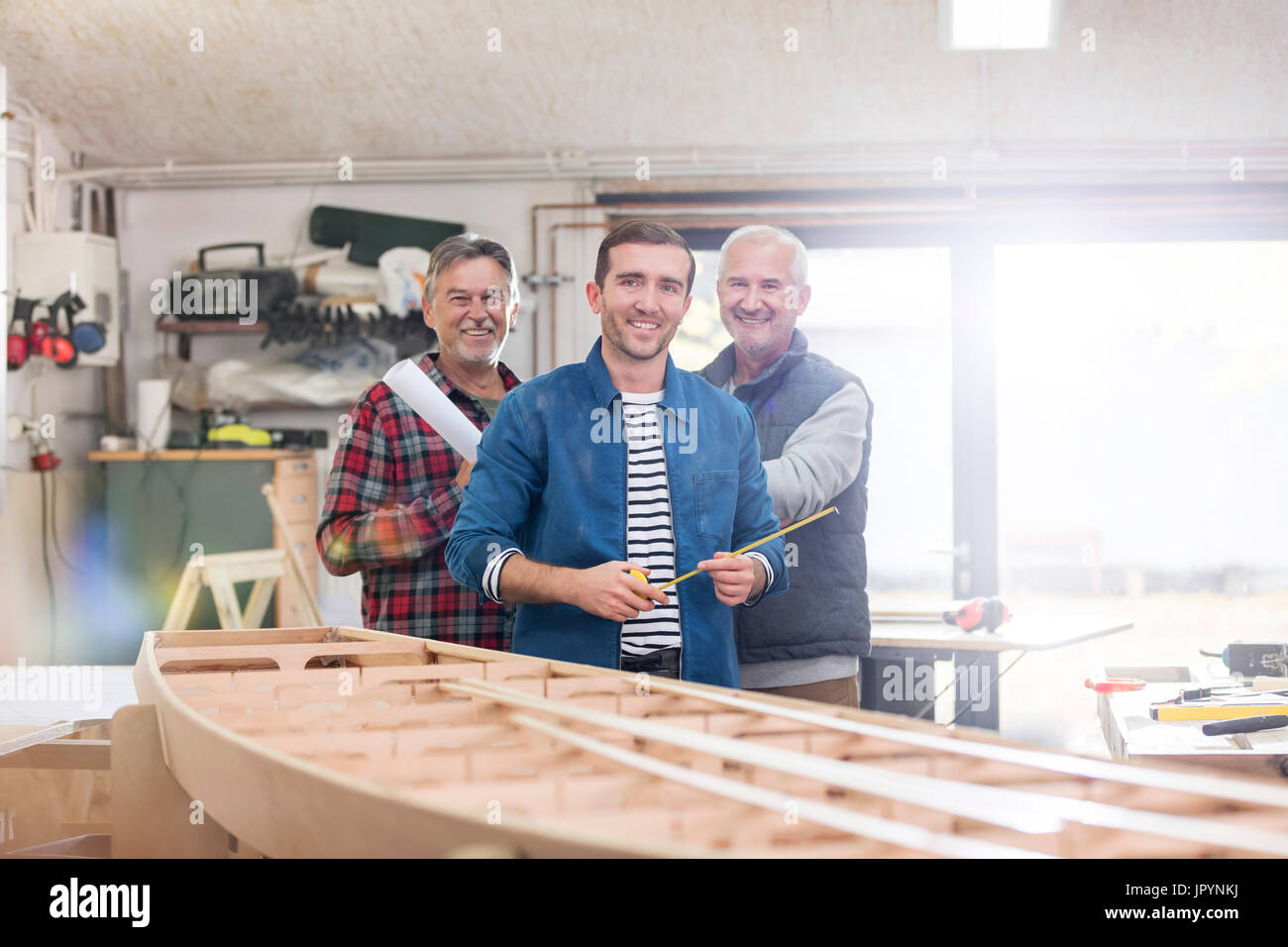 Portrait smiling male charpentiers travaillant au bateau en bois dans l'atelier Banque D'Images