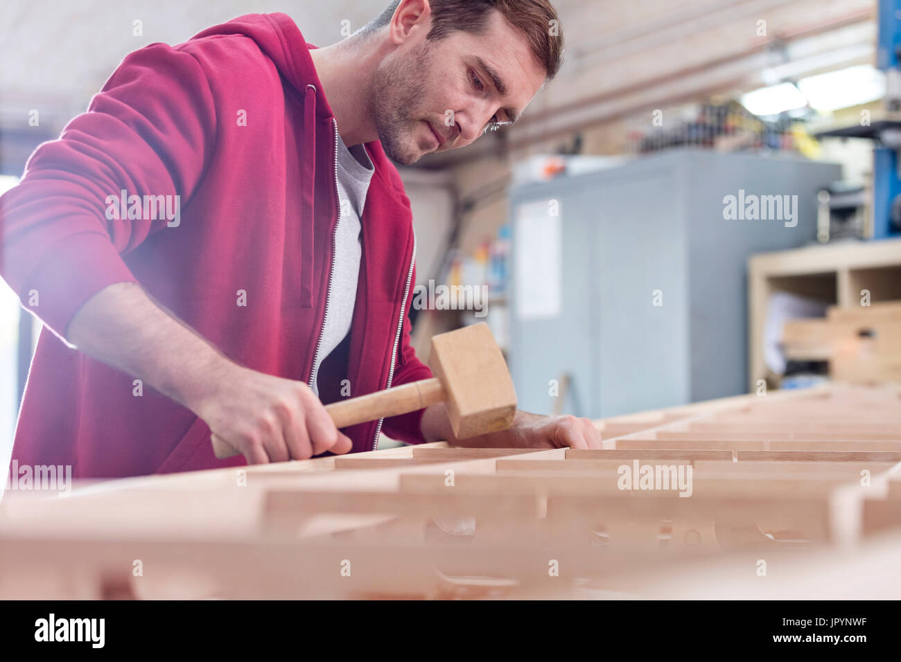 Male carpenter en utilisant du bois de maillet sur voile en atelier Banque D'Images