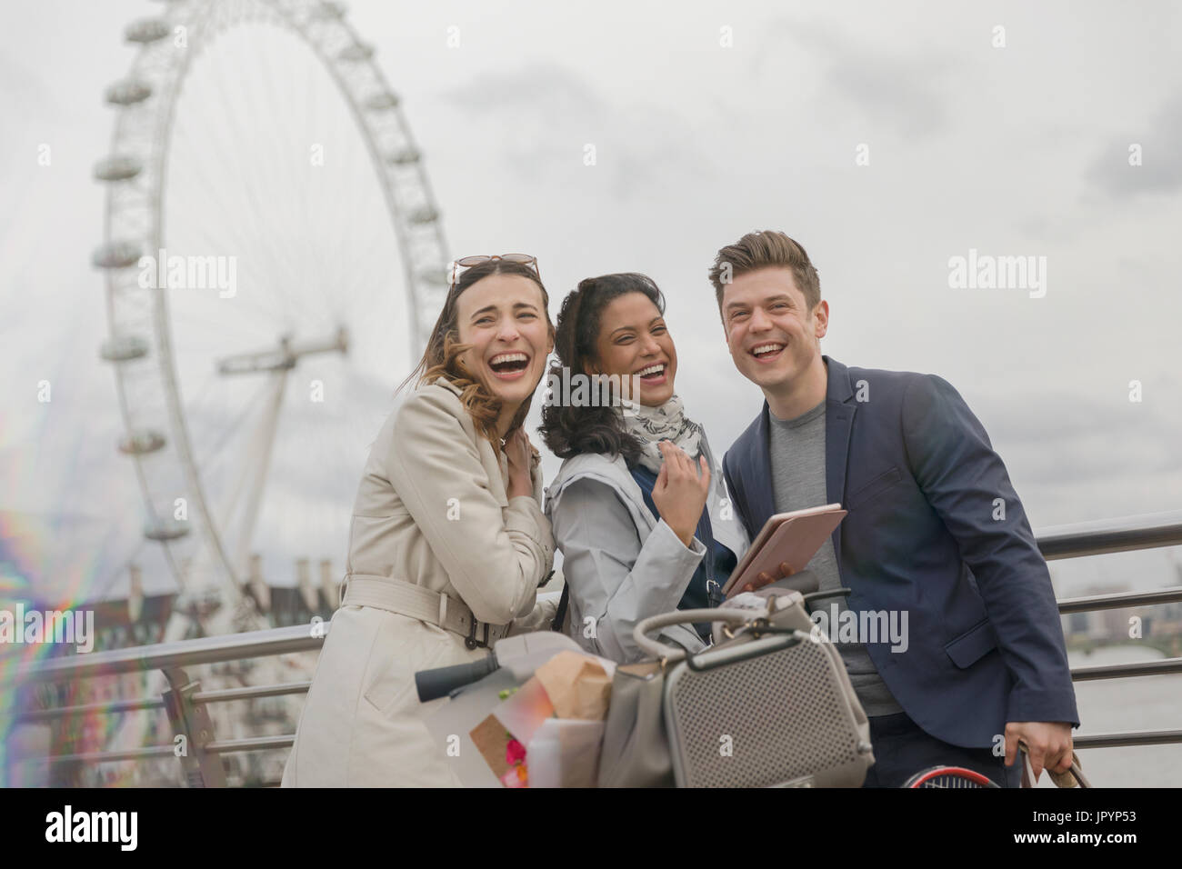 Portrait of laughing friends with digital tablet près de roue du millénaire, London, UK Banque D'Images
