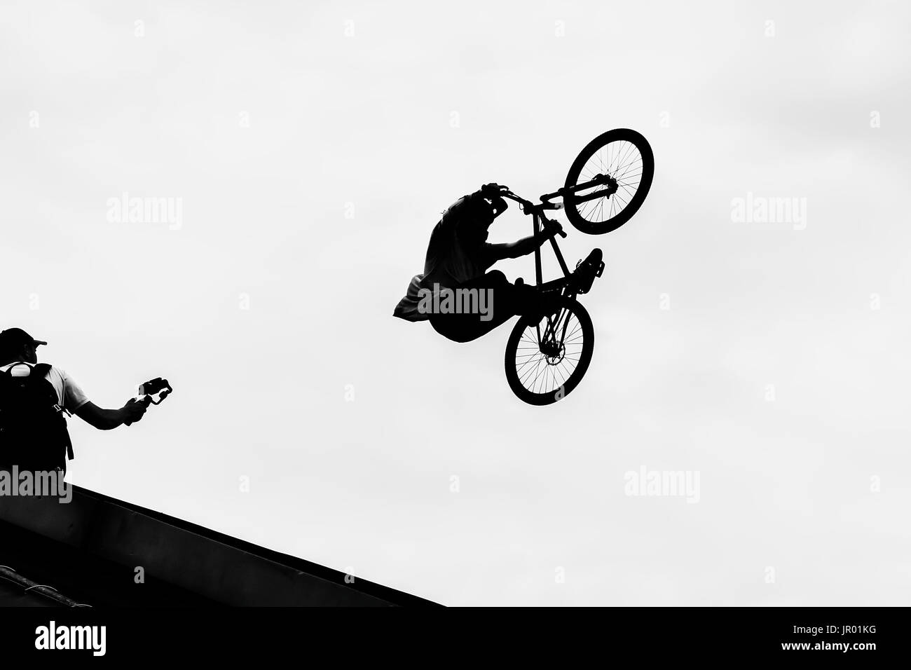 Vélo BMX sautant dans le ciel sur la grande vitesse, noir et blanc silhouette. Extrême Banque D'Images