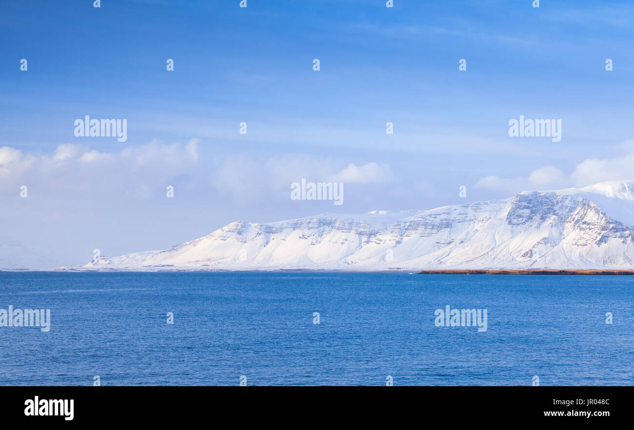 Paysage côtier islandaise avec montagnes enneigées sous ciel bleu. District de Reykjavik, Islande Banque D'Images