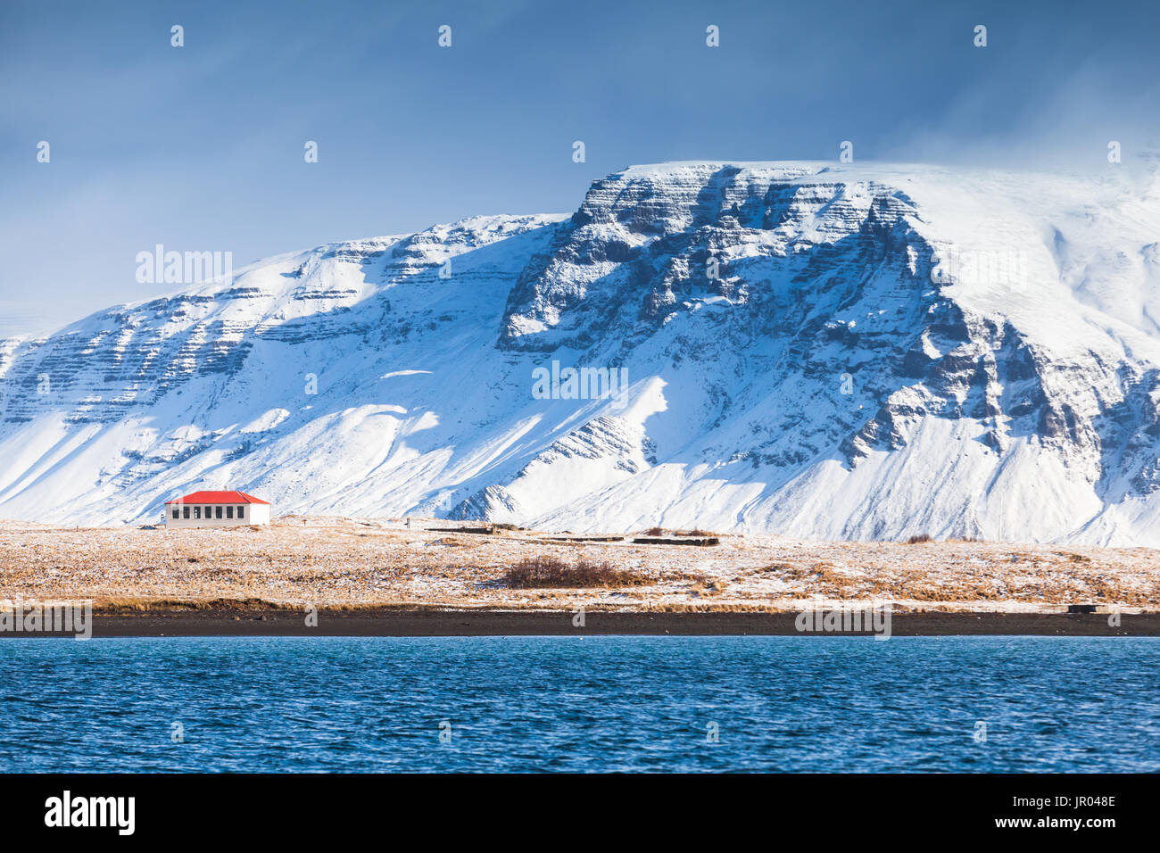 Paysage islandais côtières avec les montagnes enneigées et living house sous ciel bleu. District de Reykjavik, Islande Banque D'Images