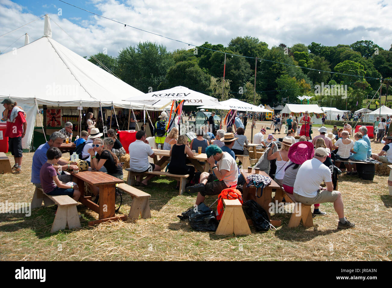 Les familles profitent du soleil assis boire et manger à l'extérieur les tentes et chapiteaux au Port Eliot Cornwall Festival UK Banque D'Images