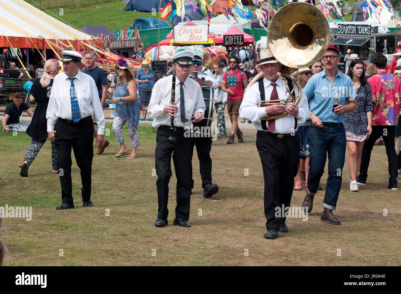 Les membres de la bande de laiton portant leurs instruments par la foule au Port Eliot Cornwall Festival uk Banque D'Images