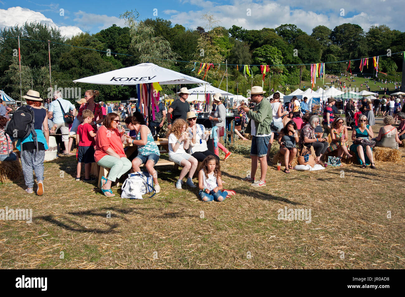 Les familles profitent du soleil assis boire et manger à l'extérieur les tentes et chapiteaux au Port Eliot Cornwall Festival UK Banque D'Images