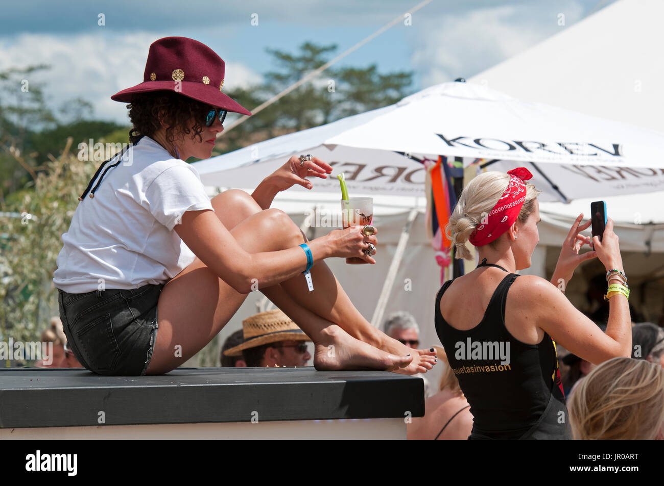 Une fille PIMMS potable portant des shorts et un chapeau d'été au Port Eliot Cornwall Festival UK Banque D'Images