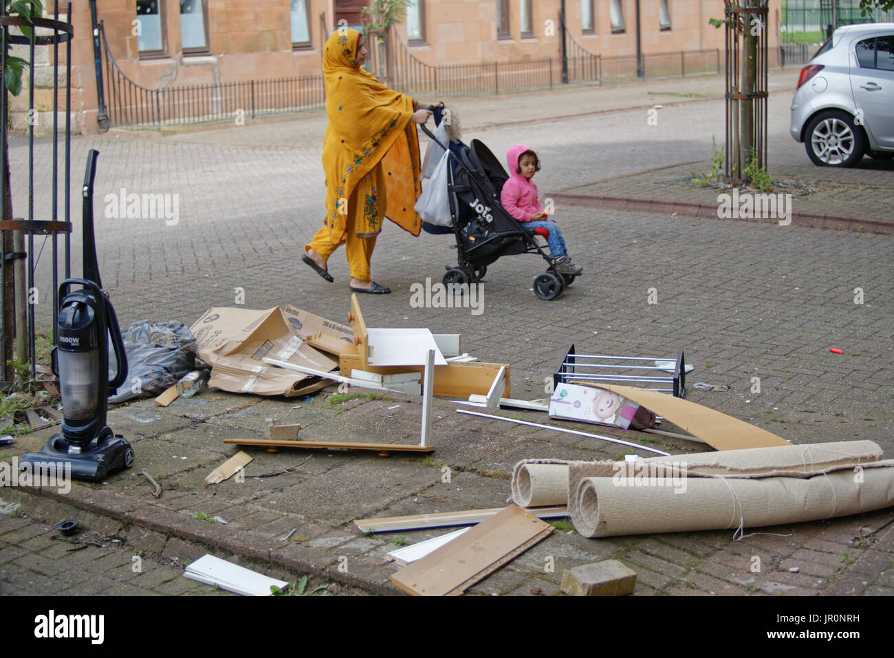 Glasgow govanhill famille asiatique vêtue de réfugiés foulard hijab sur street au Royaume-Uni scène quotidienne carrying shopping bags Banque D'Images