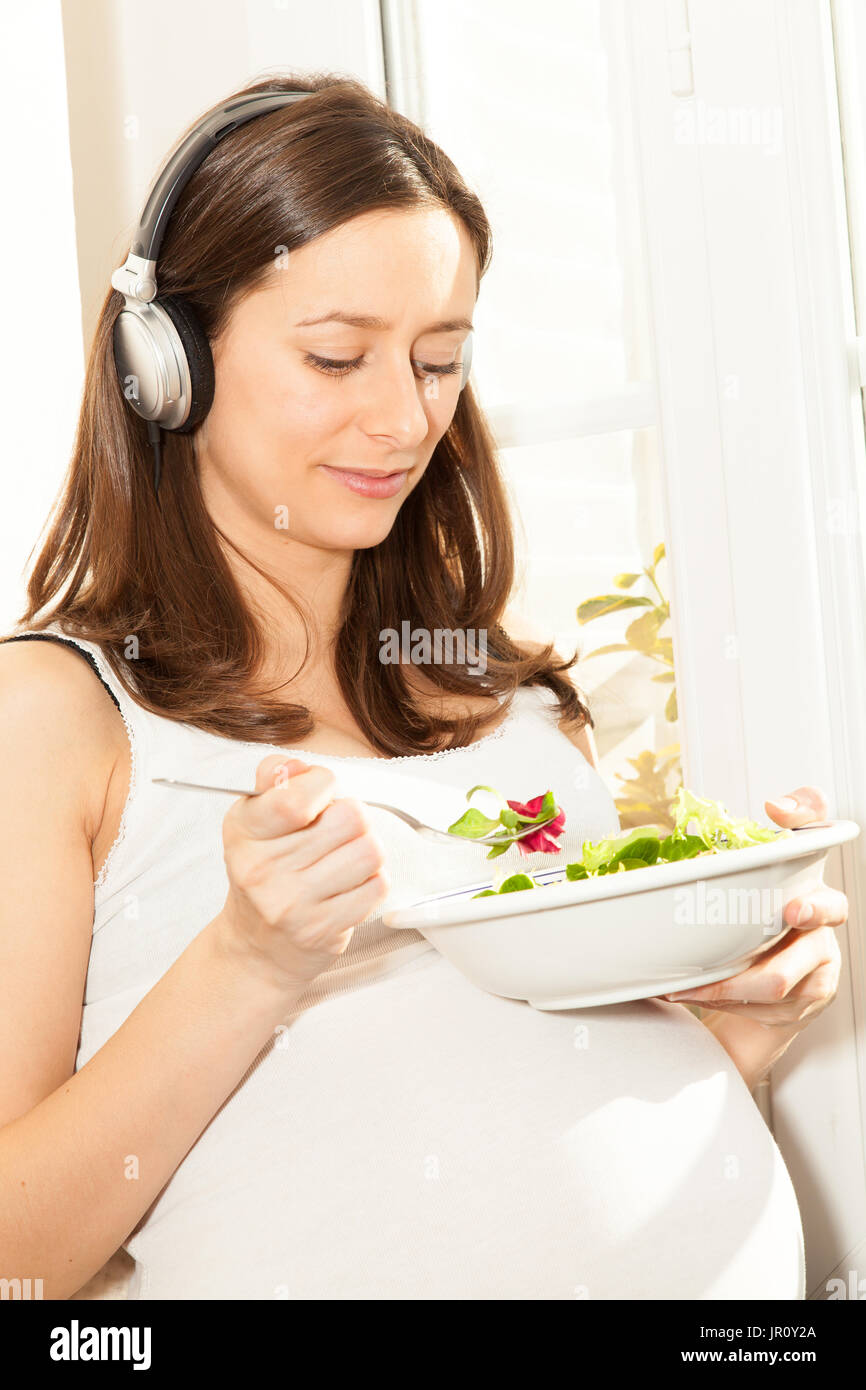 Femme enceinte salade manger et écouter de la musique Banque D'Images
