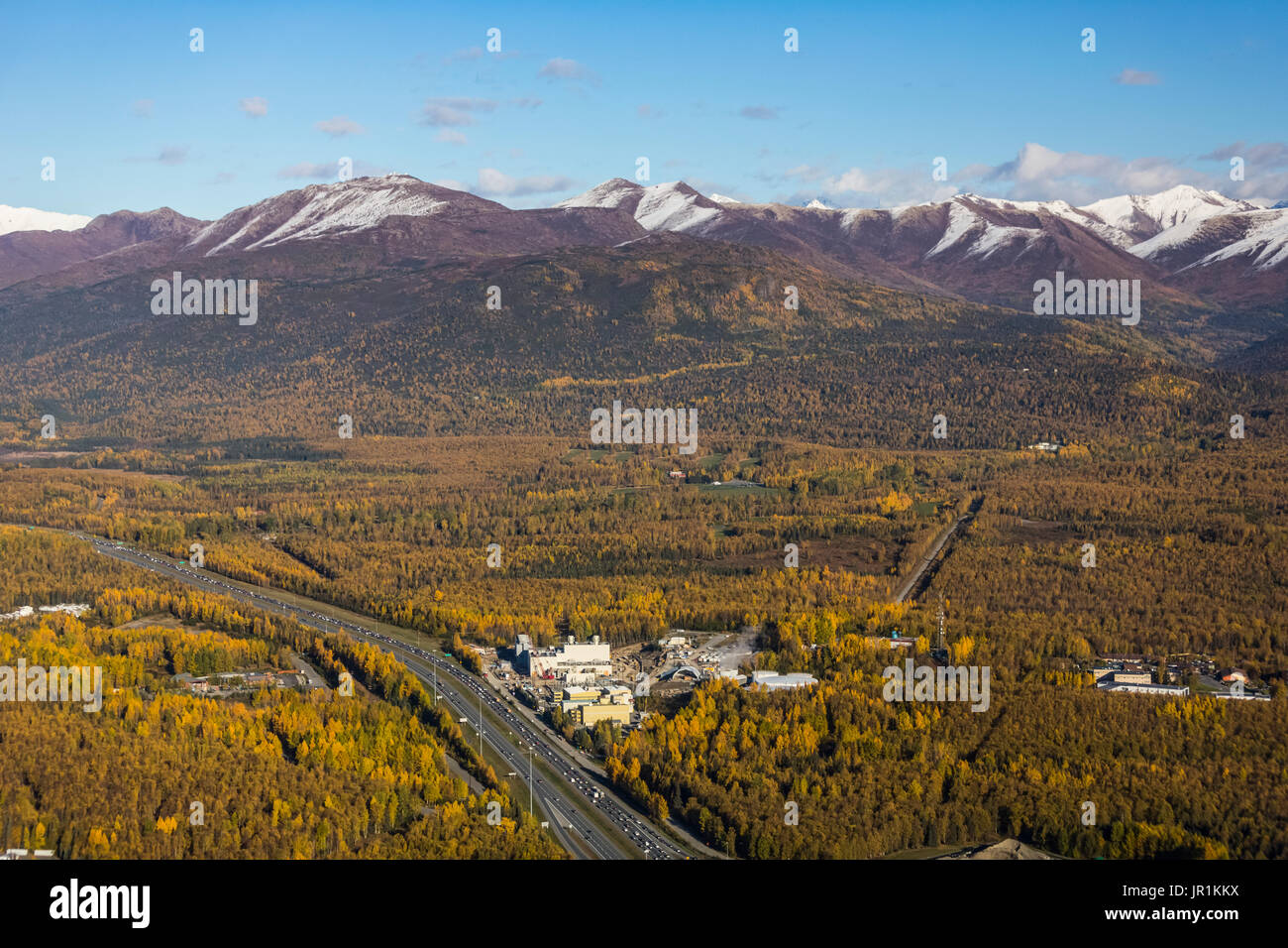 Vue aérienne de la Glenn Highway passant devant la centrale électrique municipale avec les montagnes de Chugach en arrière-plan, au centre-sud d'Ala... Banque D'Images