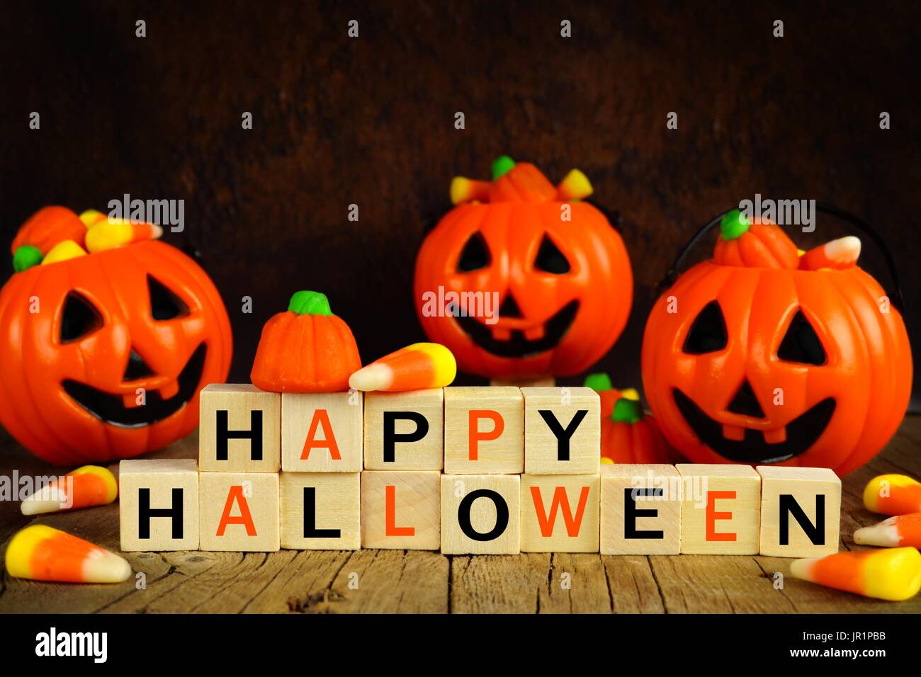 Happy Halloween des blocs en bois avec des bonbons maïs et jack o lantern porteurs sur un fond noir et orange Banque D'Images