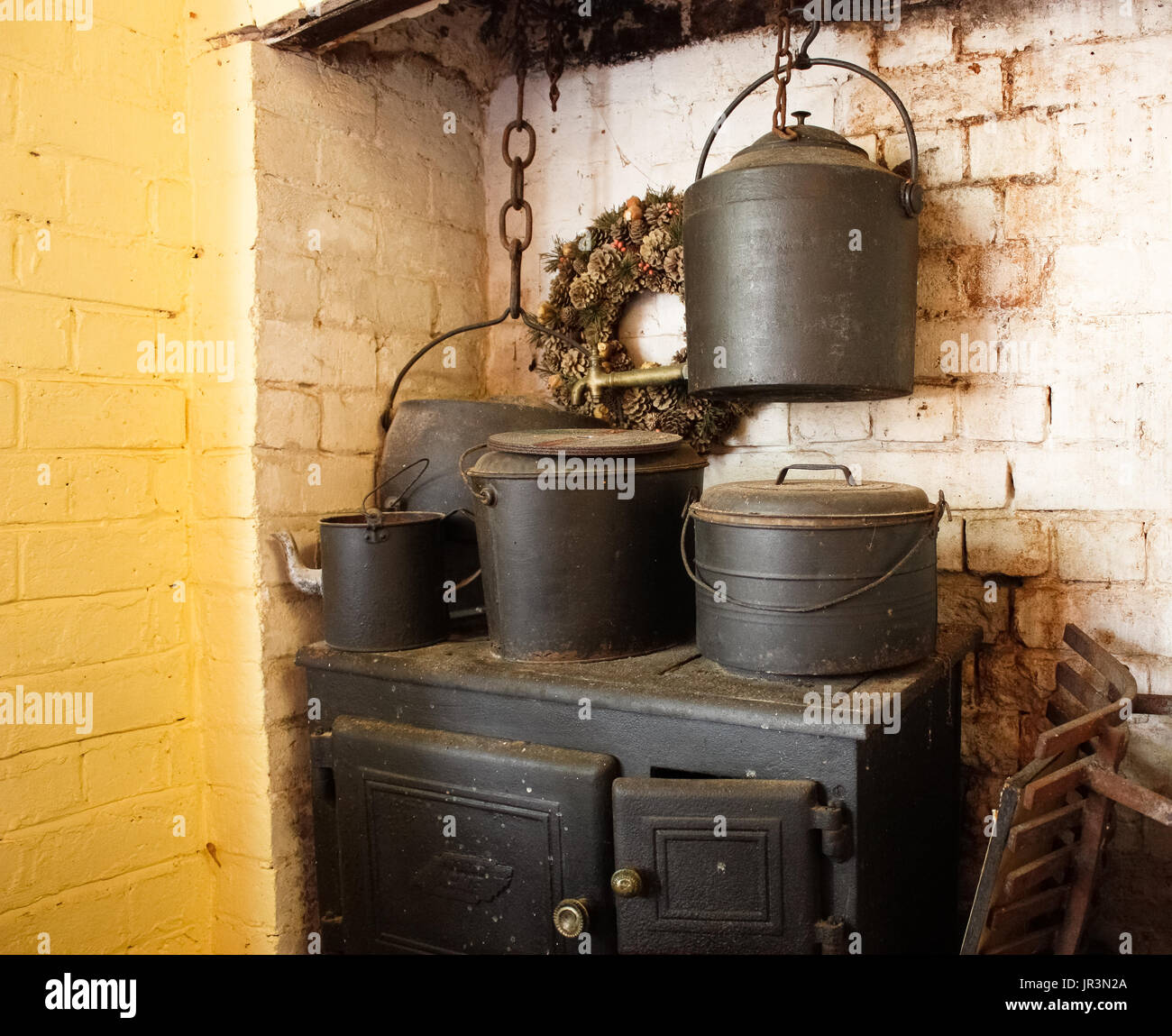 Cuisine cuisinière bois à l'ancienne avec des pots en fonte contre brick wall Banque D'Images