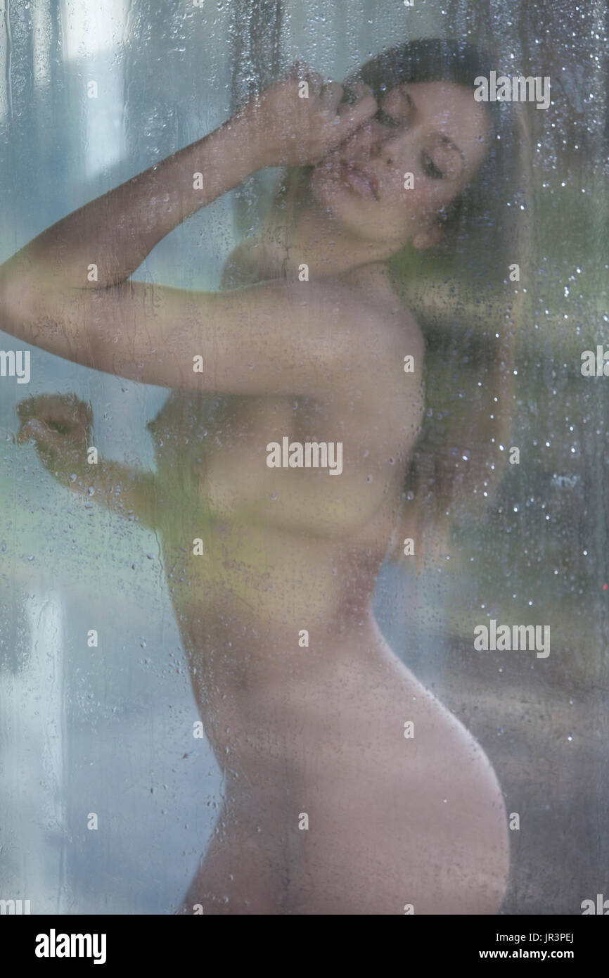 Femme nue derrière un verre humide Banque D'Images