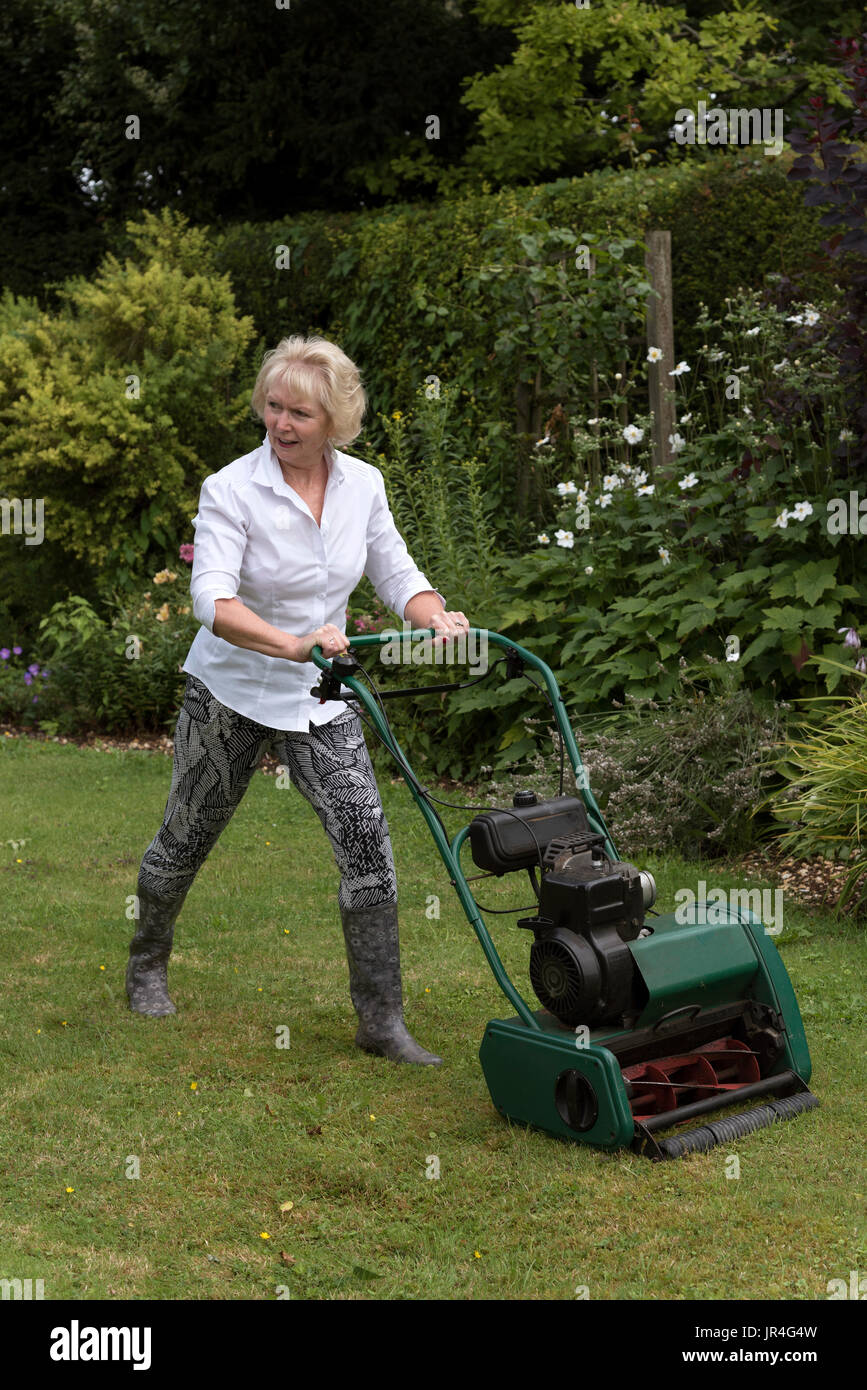 Coupe femme une pelouse avec une tondeuse à essence Photo Stock - Alamy