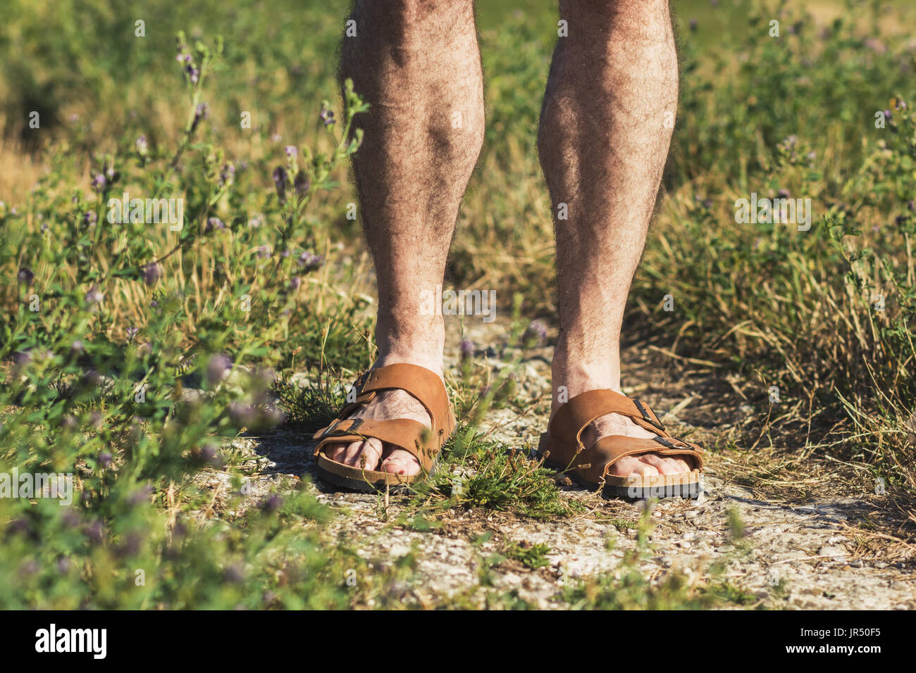 Dans les jambes des hommes sandales en cuir brun debout sur un sentier Banque D'Images