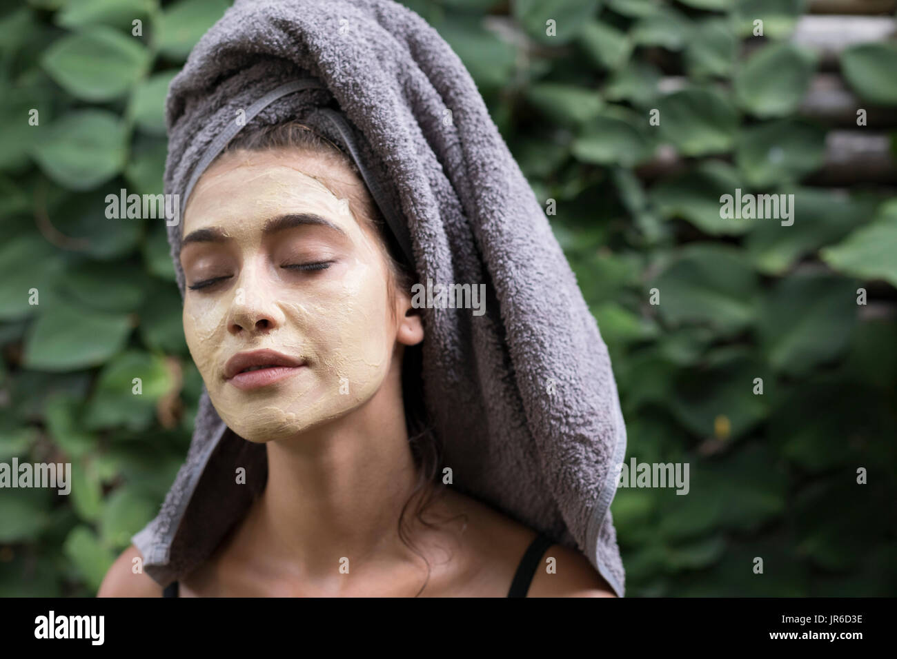 Portrait d'une femme avec un masque de visage et une serviette sur la tête. Banque D'Images