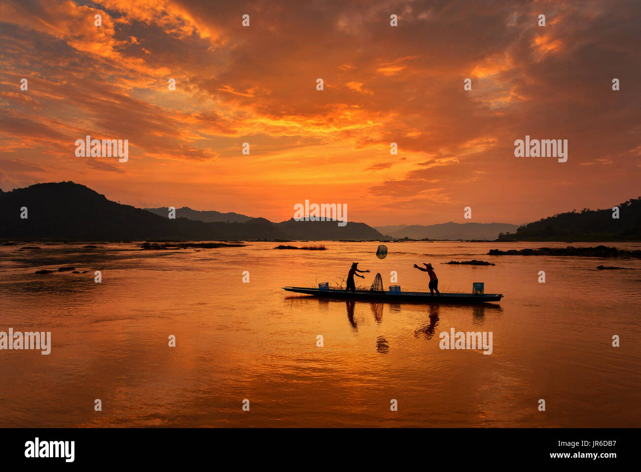 Silhouette de deux pêcheurs à bord d'un bateau au coucher du soleil, la Thaïlande Banque D'Images