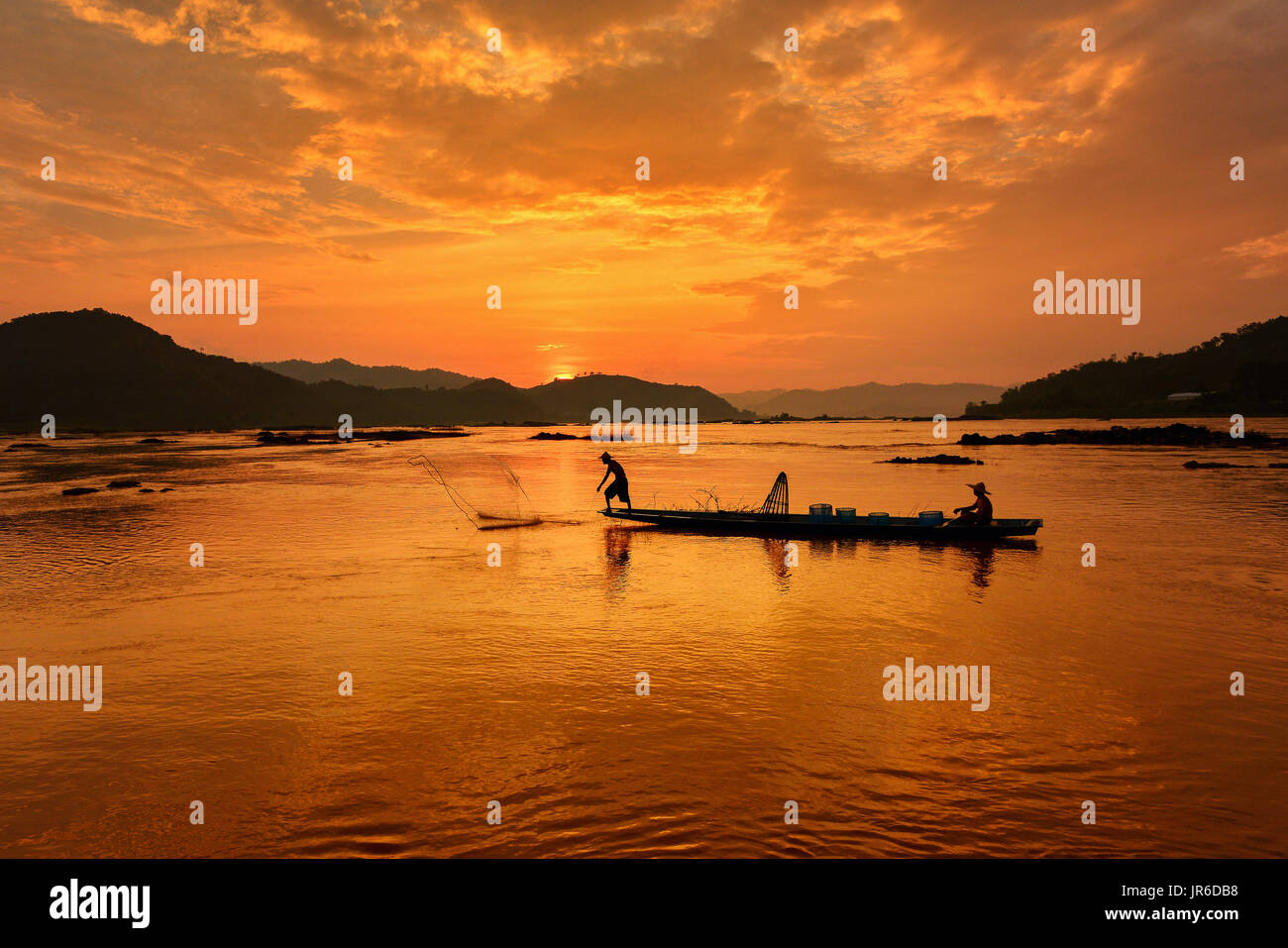 Silhouette de deux pêcheurs à bord d'un bateau au coucher du soleil, la Thaïlande Banque D'Images