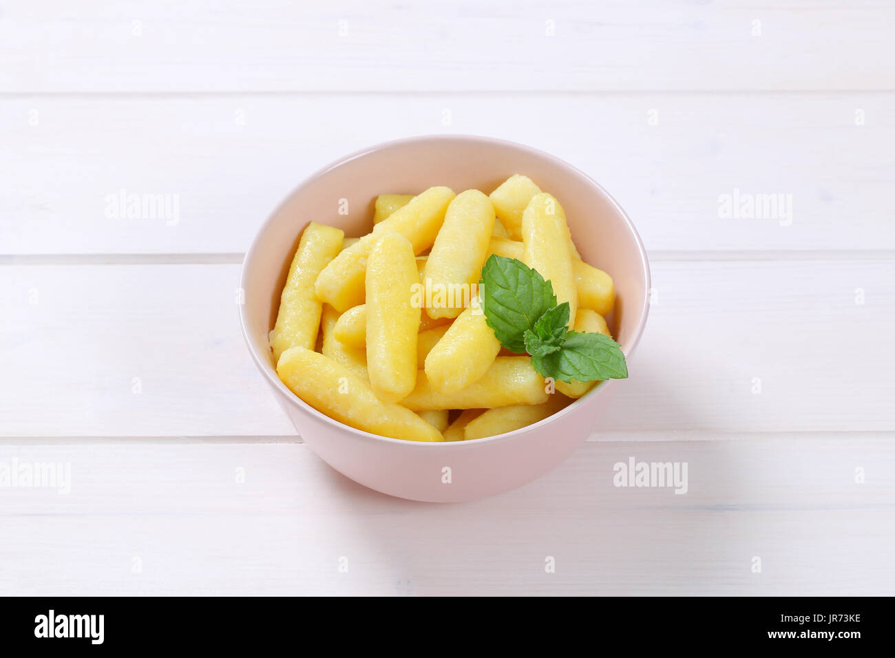 Bol de pommes de terre cuites ou gnocchi cônes sur fond de bois blanc Banque D'Images