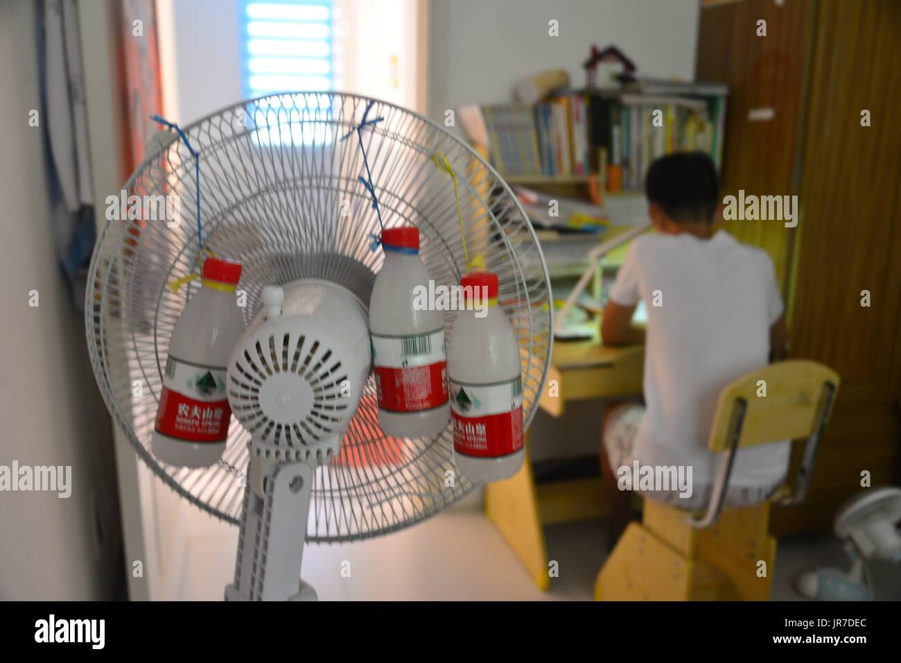 Qingdao, Qingdao, Chine. 4e août, 2017. Liaocheng, CHINE-Août 4 2017 :  (usage éditorial uniquement. Chine OUT) .Un élève invente un self-made 'air  conditionné' par la fixation des bouteilles d'eau glacée derrière un