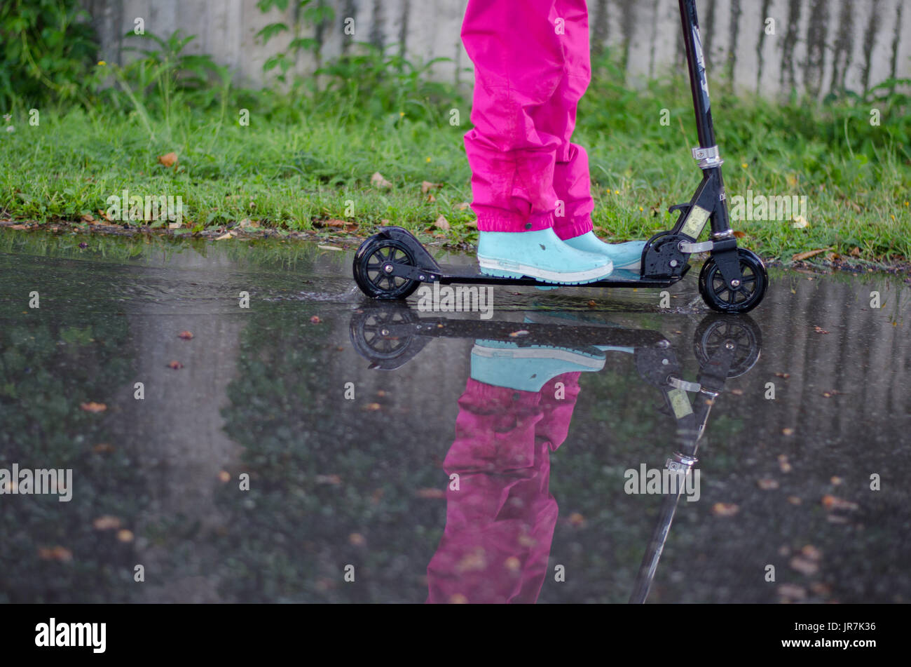 Stockholm, Suède. 4e août, 2017. Jour de pluie à Stockholm après plusieurs jours avec des chaudes journées d'été sans pluie. Fille en vêtements de pluie colorées et des bottes en caoutchouc rides son kick-bike dans les rues des pluies. Credit : Jari Juntunen/Alamy Live News Banque D'Images