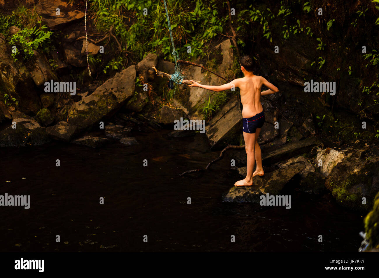 Un jeune garçon jouant sur la balançoire à Lumb Falls, un endroit de beauté locaux et la natation trou près de Calderdale, Hebden Bridge, UK Banque D'Images