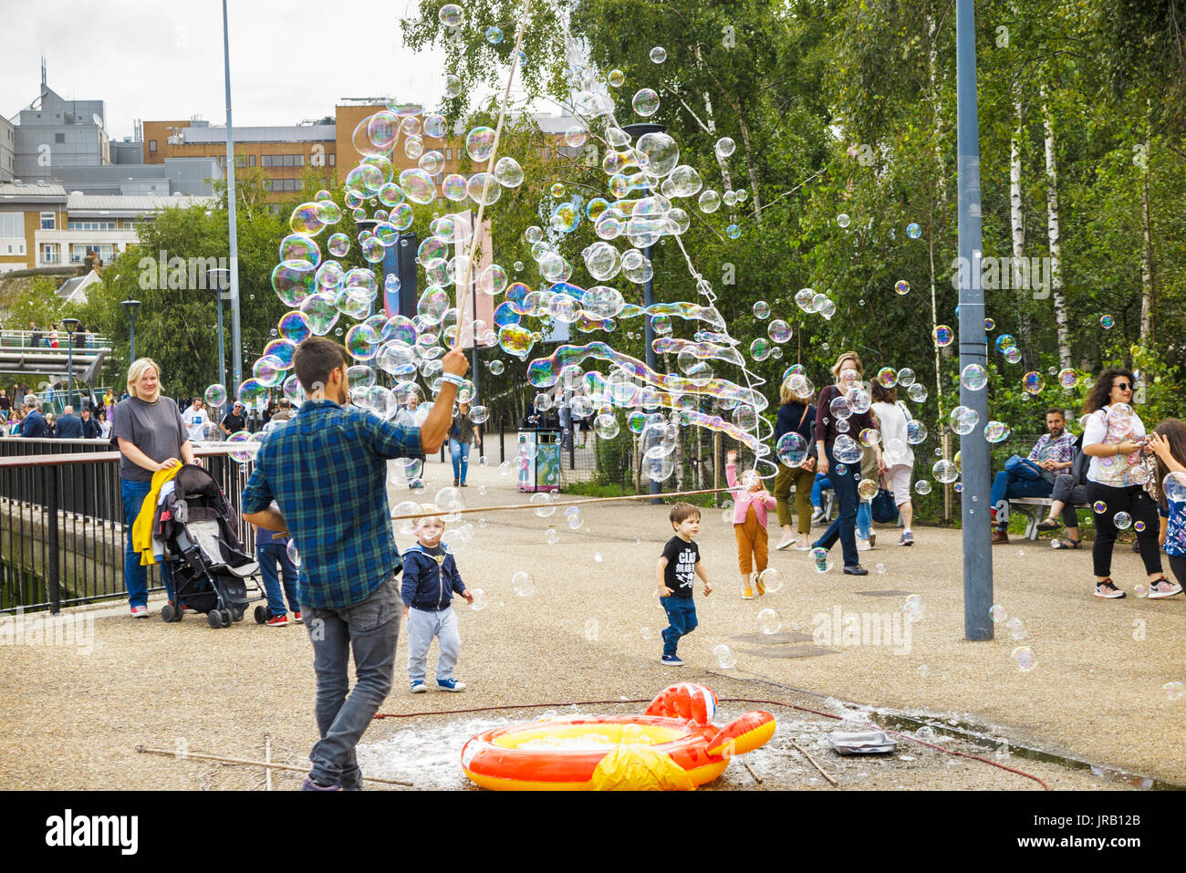 Artiste de rue aux enfants conseils sollicitation en soufflant de grandes bulles colorées, Bankside, remblai, South Bank, Londres SE1, UK Banque D'Images