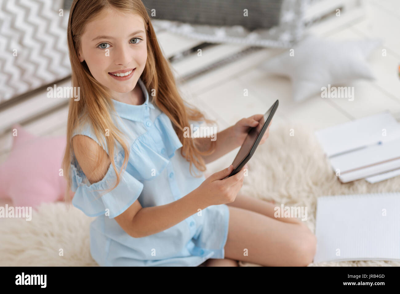 Adorable girl with digital tablet souriant largement pour l'appareil photo Banque D'Images