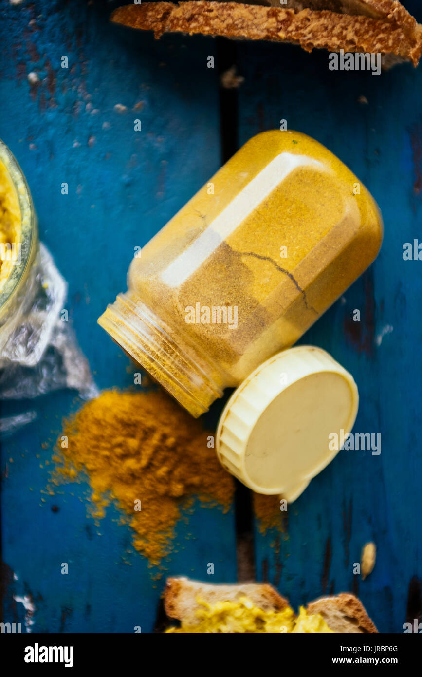 Vue de dessus d'épices curry jaune sur un fond bleu rouillé versé d'un récipient Banque D'Images