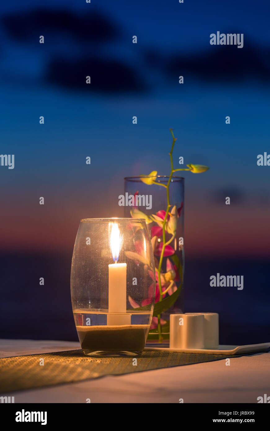 Bougie sur une table au restaurant avec vue sur le coucher du soleil sur l'île de Koh Kood, Thaïlande Banque D'Images