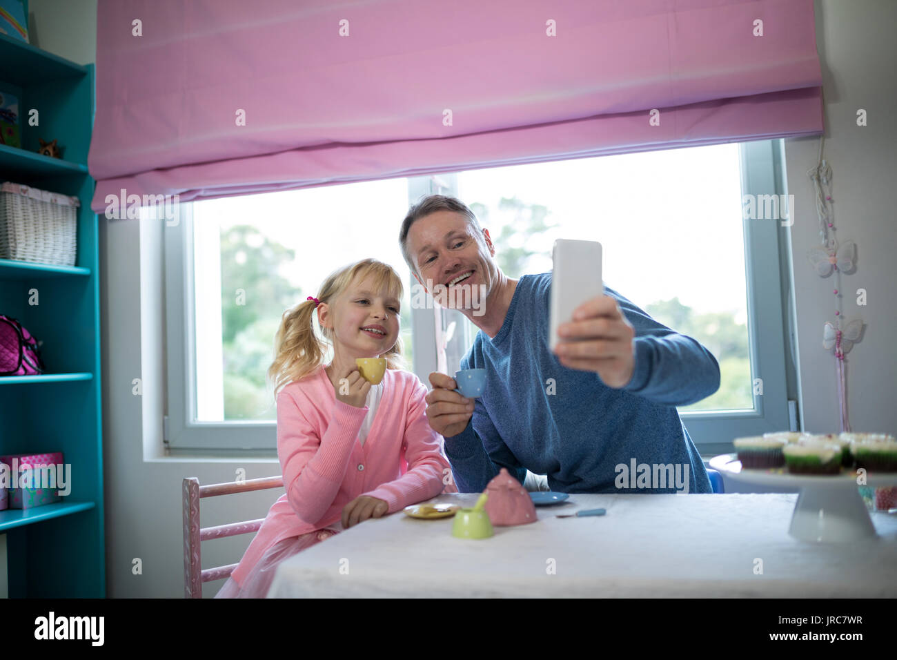 Jeune fille enjouée et père de prendre un en jouant avec un selfies toy Set de cuisine Banque D'Images