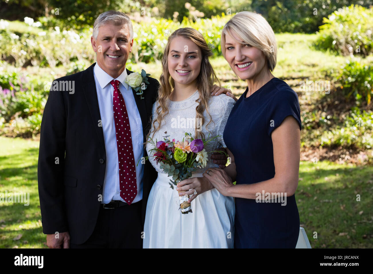 Portrait of bride standing avec ses parents en park Banque D'Images