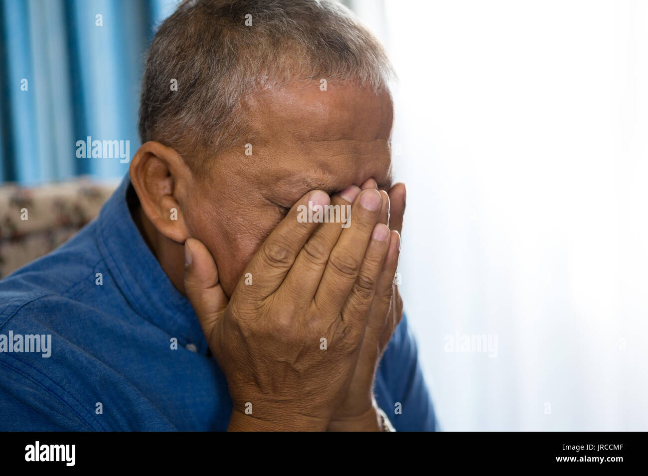 Close up of senior man bouleversé couvrant les yeux avec les mains dans la maison de soins infirmiers Banque D'Images