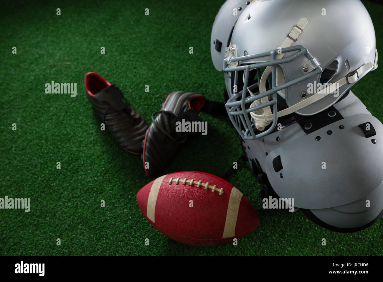 Close-up du football américain d'épaulières, tête, de football et d'écarteurs sur gazon artificiel Banque D'Images