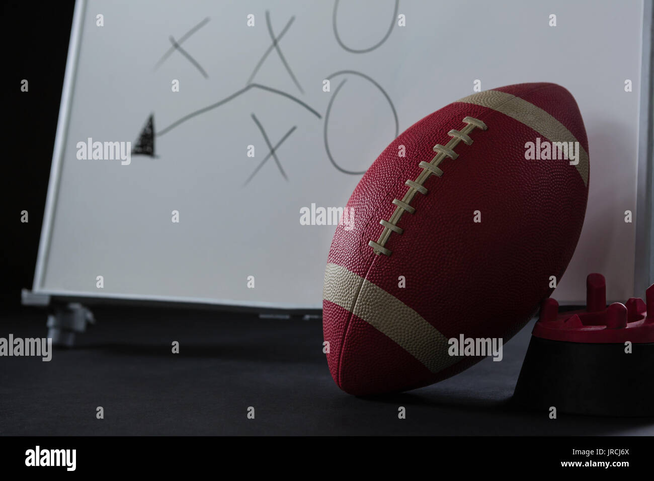 Close-up du football américain reposant sur support et stratégie de jeu dessiné sur un tableau blanc Banque D'Images