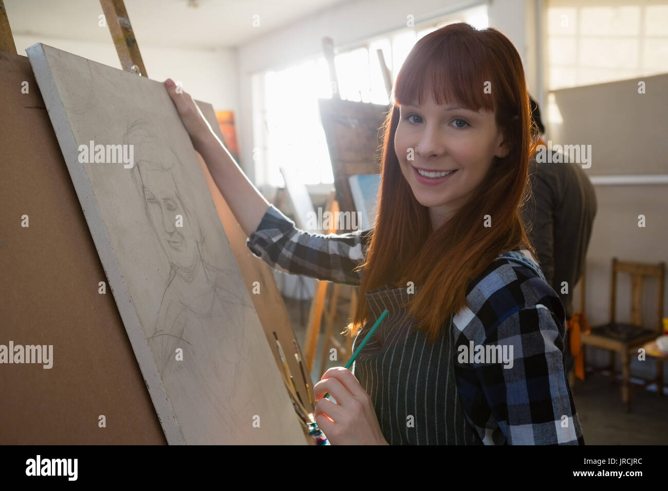 Portrait de femme peinture tout en se tenant dans la classe d'art Banque D'Images