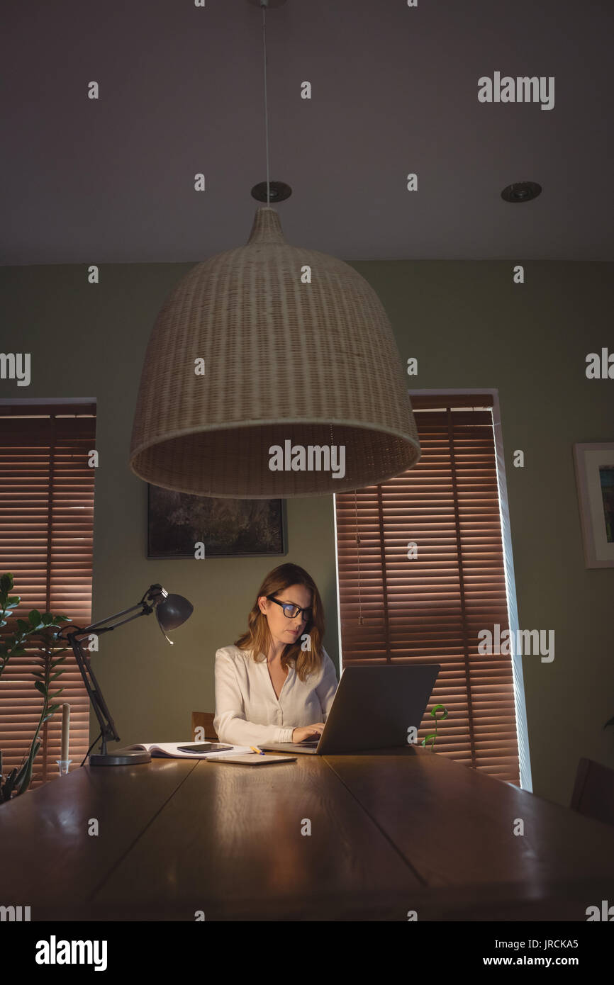 Woman using laptop in drawing room à la maison Banque D'Images