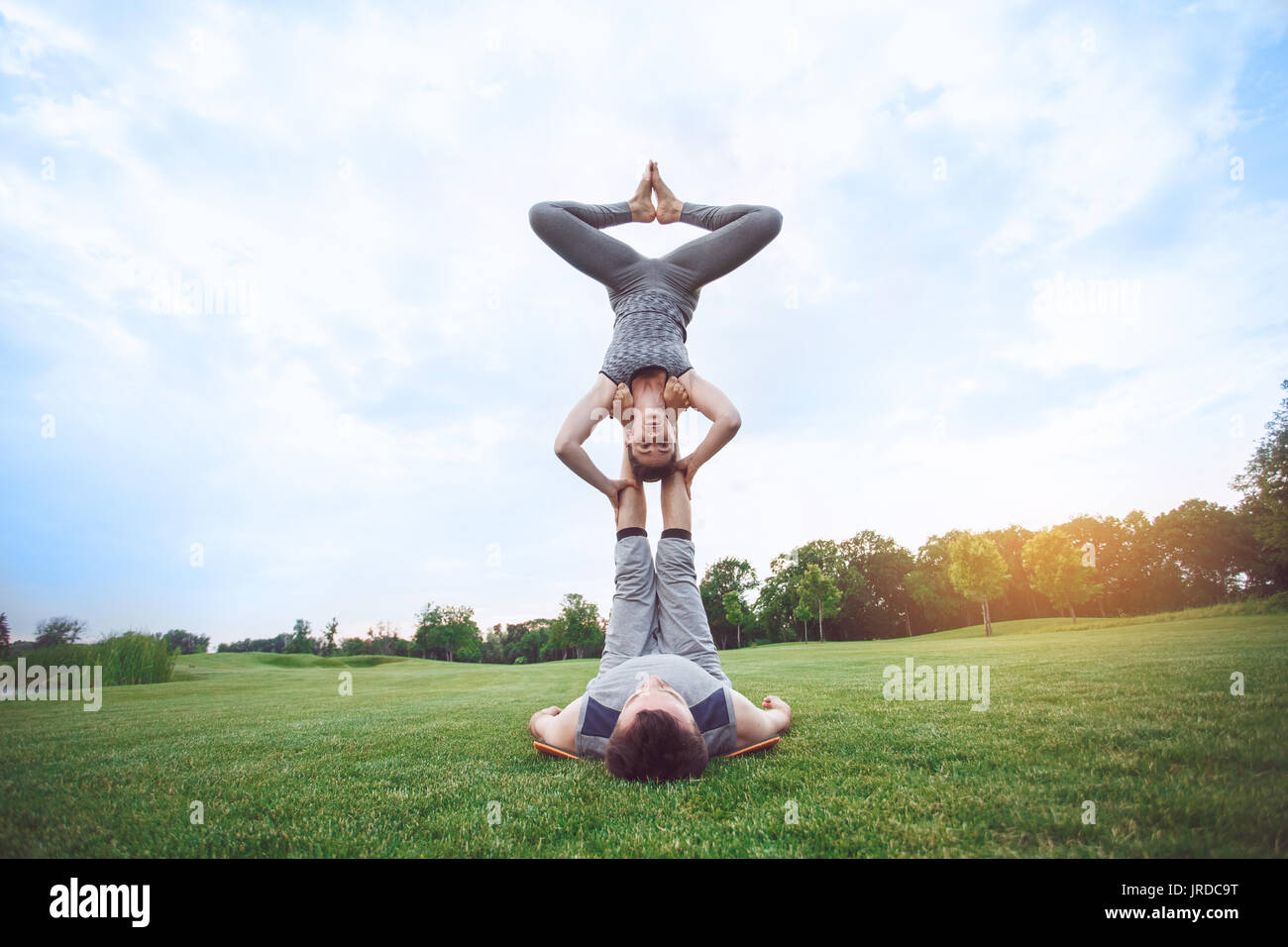 L'homme et de la femme pratique le yoga dans le parc acro Banque D'Images