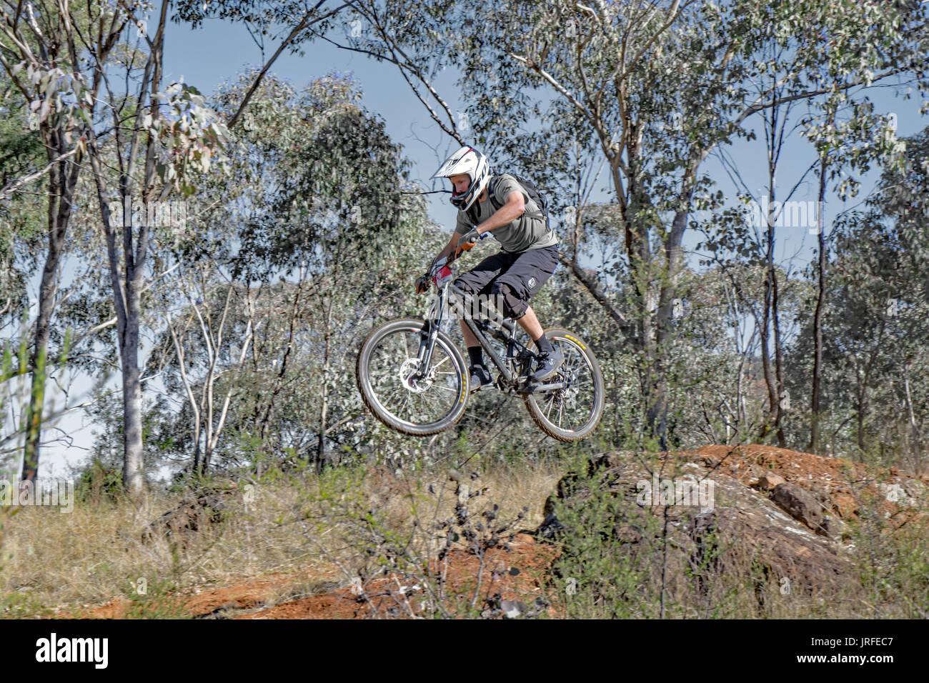 Course de vélo de montagne sautant par-dessus un rocher à Mount Borah NSW Australie. Banque D'Images
