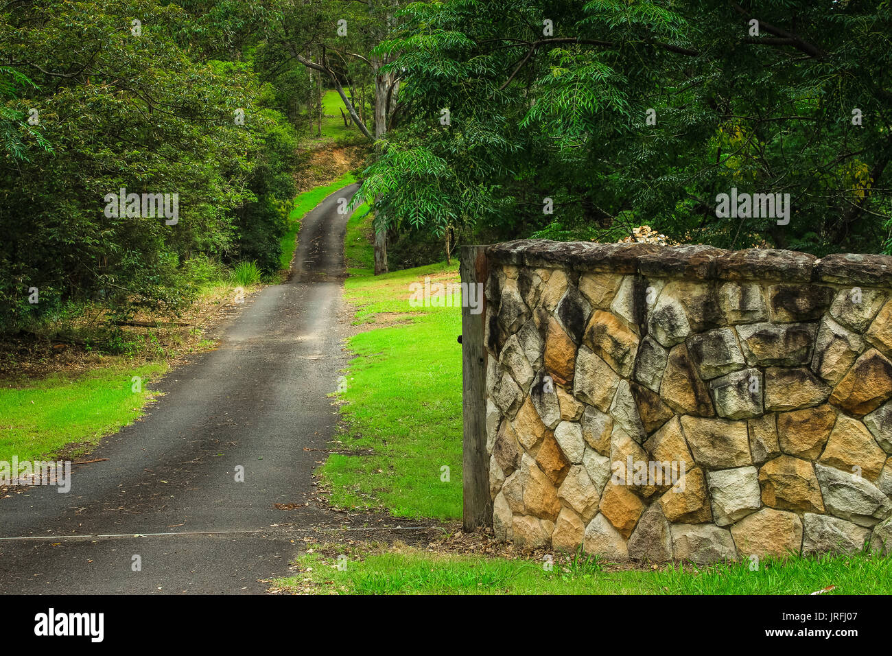 Mur de grès à l'entrée de l'espace rural allée, bordée par les arbres du jardin Banque D'Images