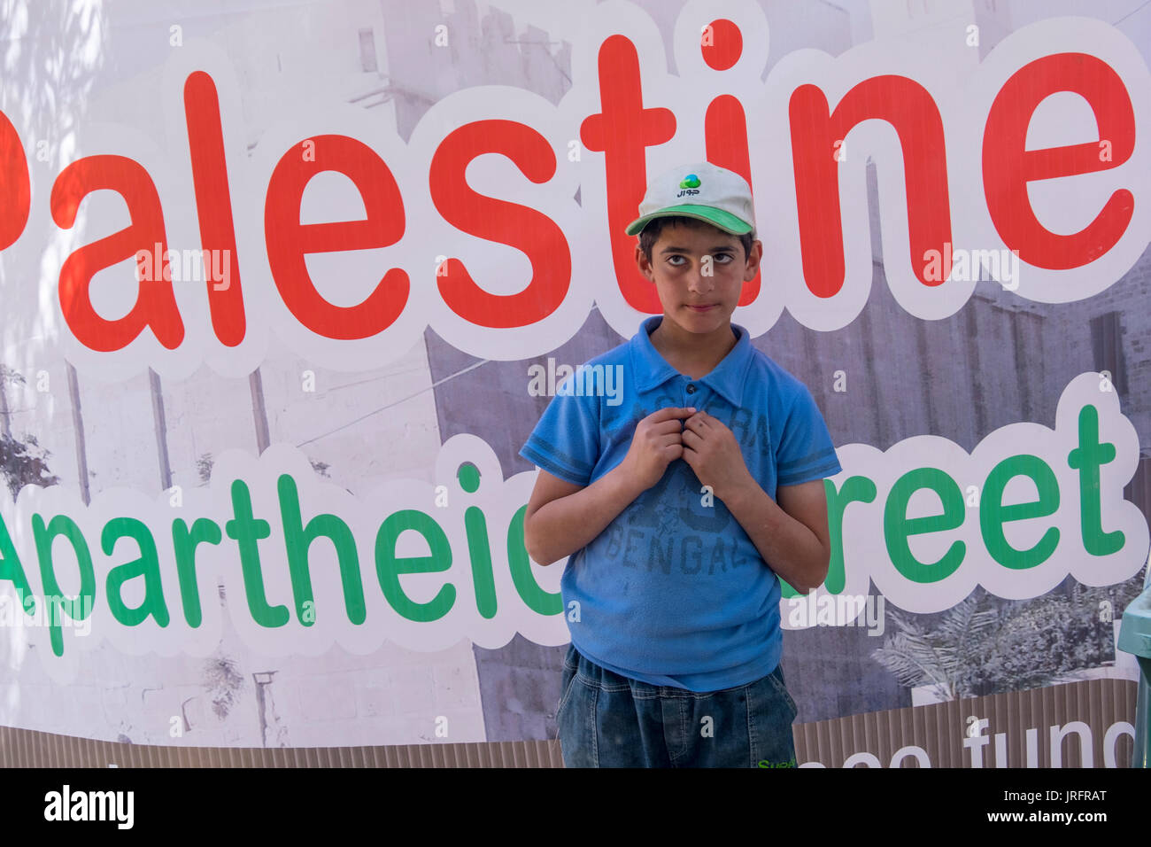 Jeune garçon palestinien debout devant un signe qui protestent contre la fermeture d'une rue centrale à Hébron, en Cisjordanie, Territoires Occupés Banque D'Images