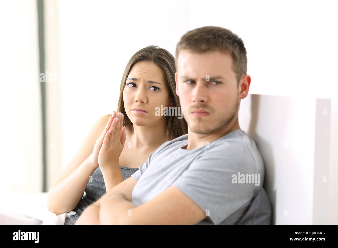 Femme mendier pour son mari en colère assis sur le lit dans un house interior Banque D'Images