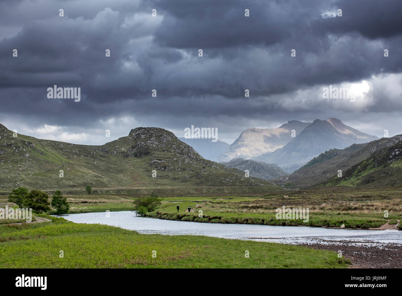 Deux promeneurs marchant sur le chemin le long de la rivière et de la pluie les nuages qui se forment dans les Highlands écossais, Wester Ross, Scotland, UK Banque D'Images
