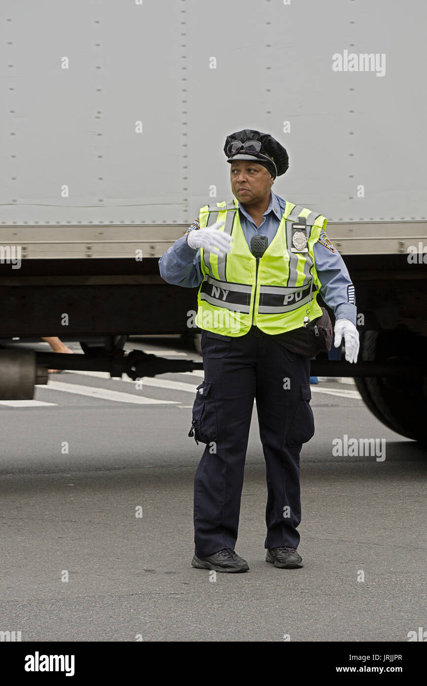 Une policière dans une veste de sécurité et gants blancs diriger la circulation sur Canal Street dans le quartier chinois, la ville de New York. Banque D'Images