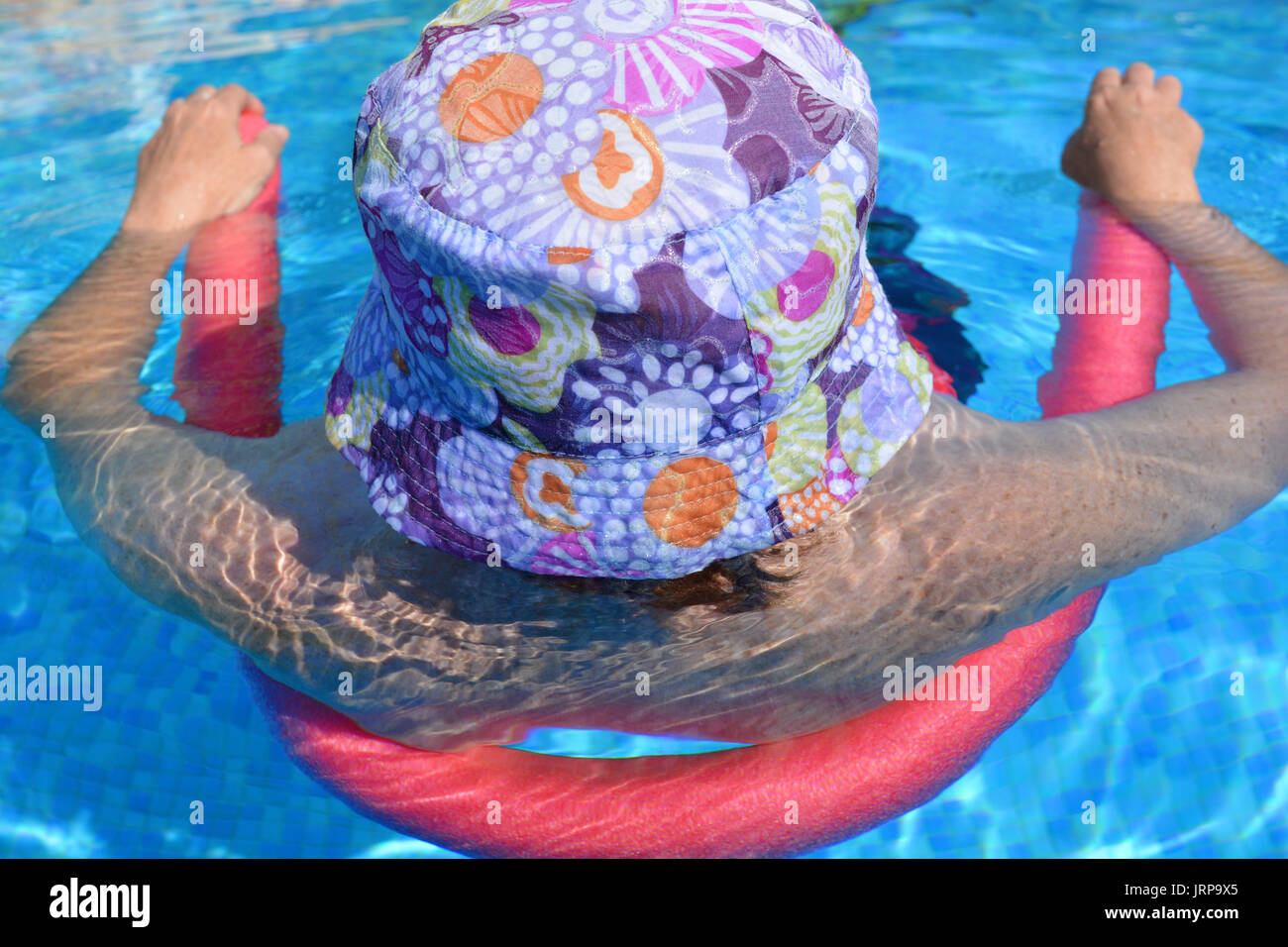 Summer vibes ! Femme flottant dans une piscine à l'aide d'une frite de piscine. Banque D'Images